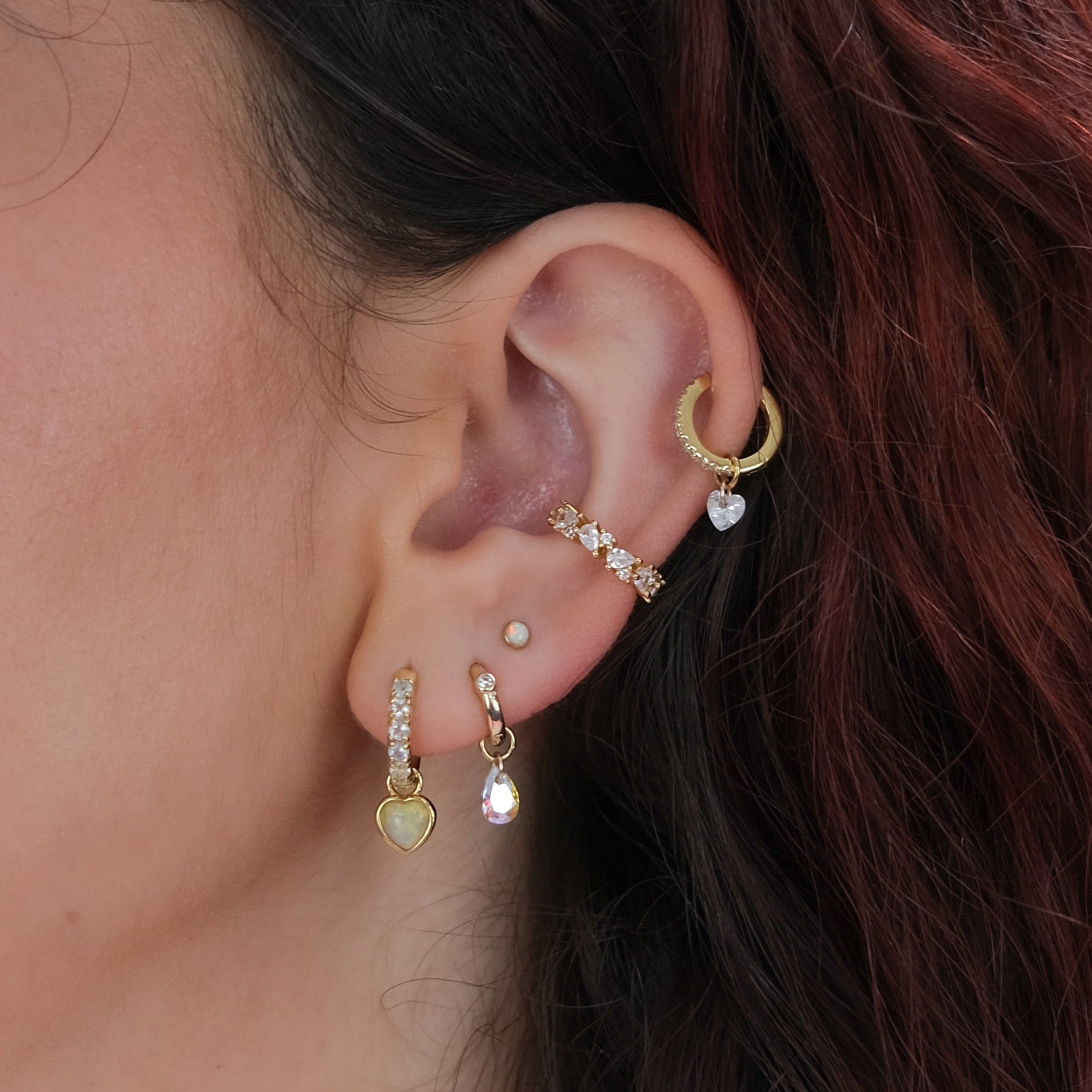 Close-up of an ear with multiple gold hoop earrings.