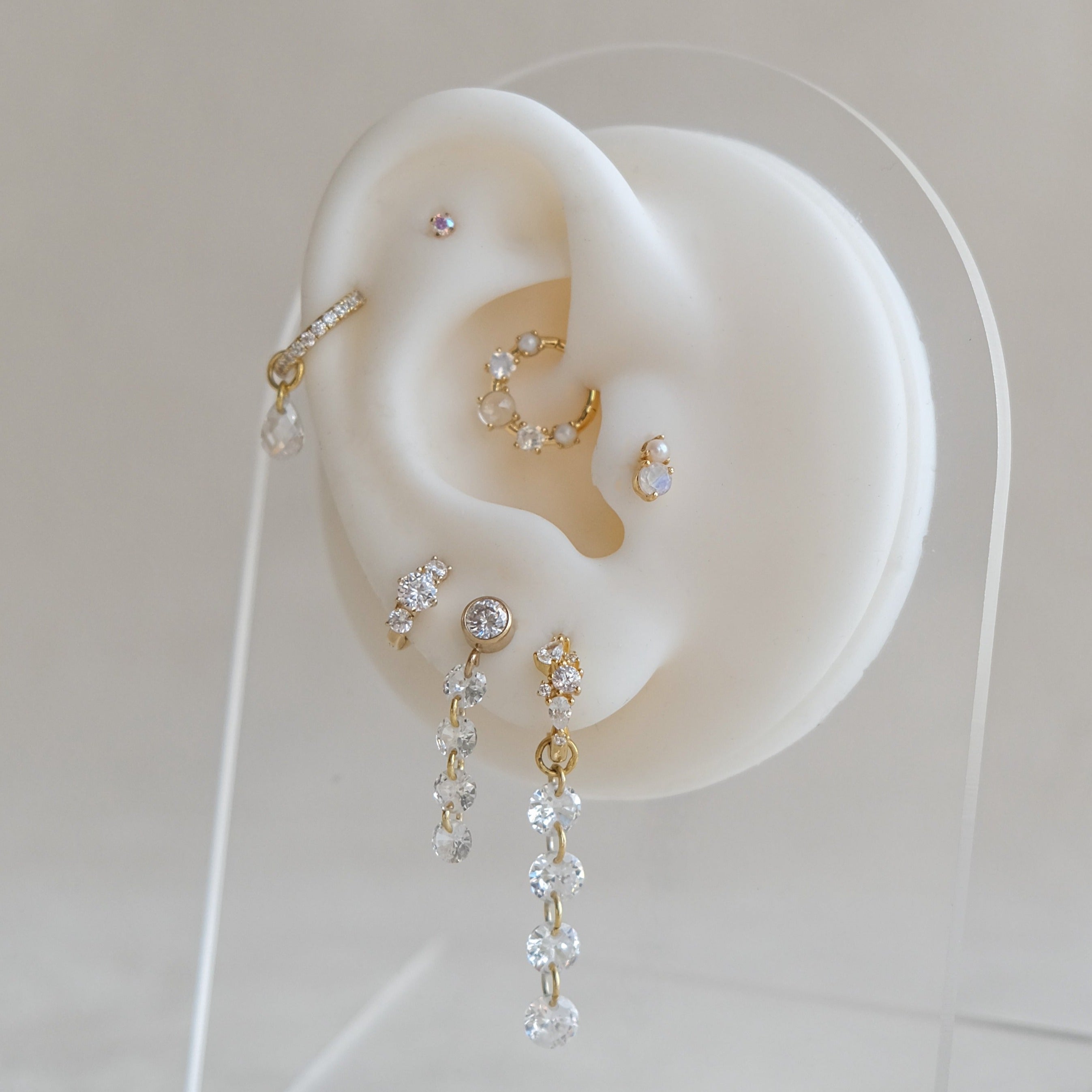 A display of Crystal Heaven London's CHLUXE • OPHELIA Cartilage Stud in 14K yellow gold adorns a white model ear, showcasing elegance and style.