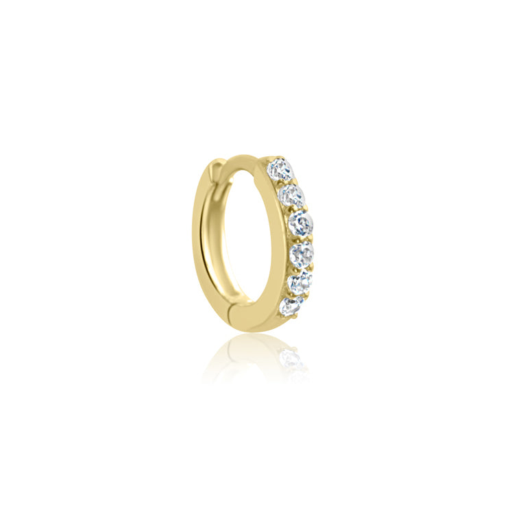 The CHLUXE Crystal Huggie Hoop by Crystal Heaven London is a 14K yellow gold earring adorned with small cubic zirconia stones on the outer edge, showcased on a reflective surface.