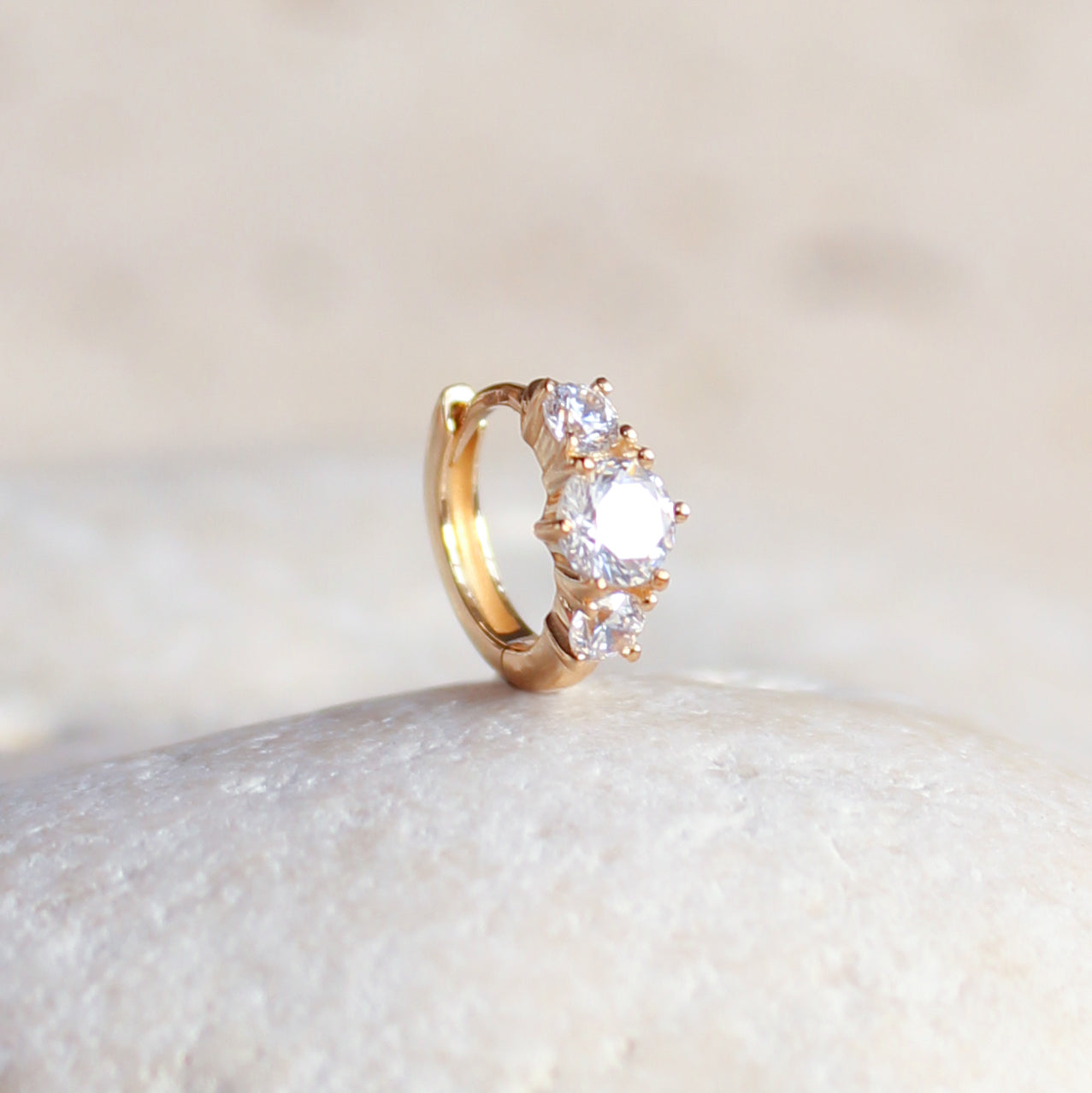 CHLUXE Stacked Crystal Huggie Hoop by Crystal Heaven London on a smooth, light stone surface.