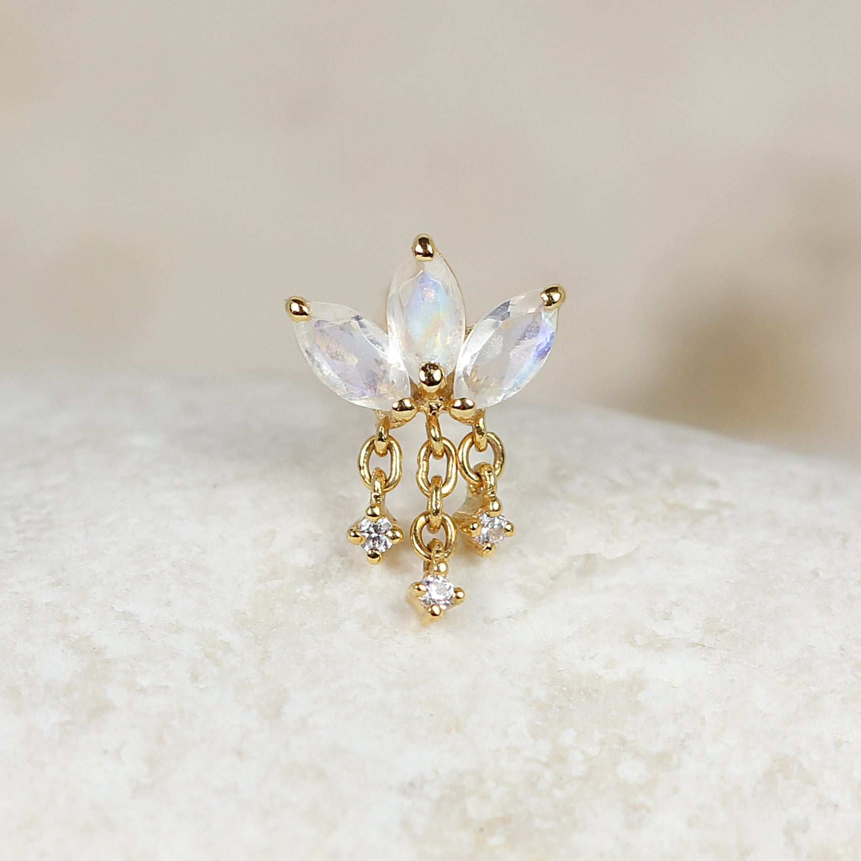 The CHLUXE • LEILANI Chain Droplet Cartilage Stud by Crystal Heaven London is a limited edition 14k yellow gold earring featuring three marquise-cut gemstones with elegant chains holding small round stones, highlighted by the enchanting beauty of rainbow moonstone.