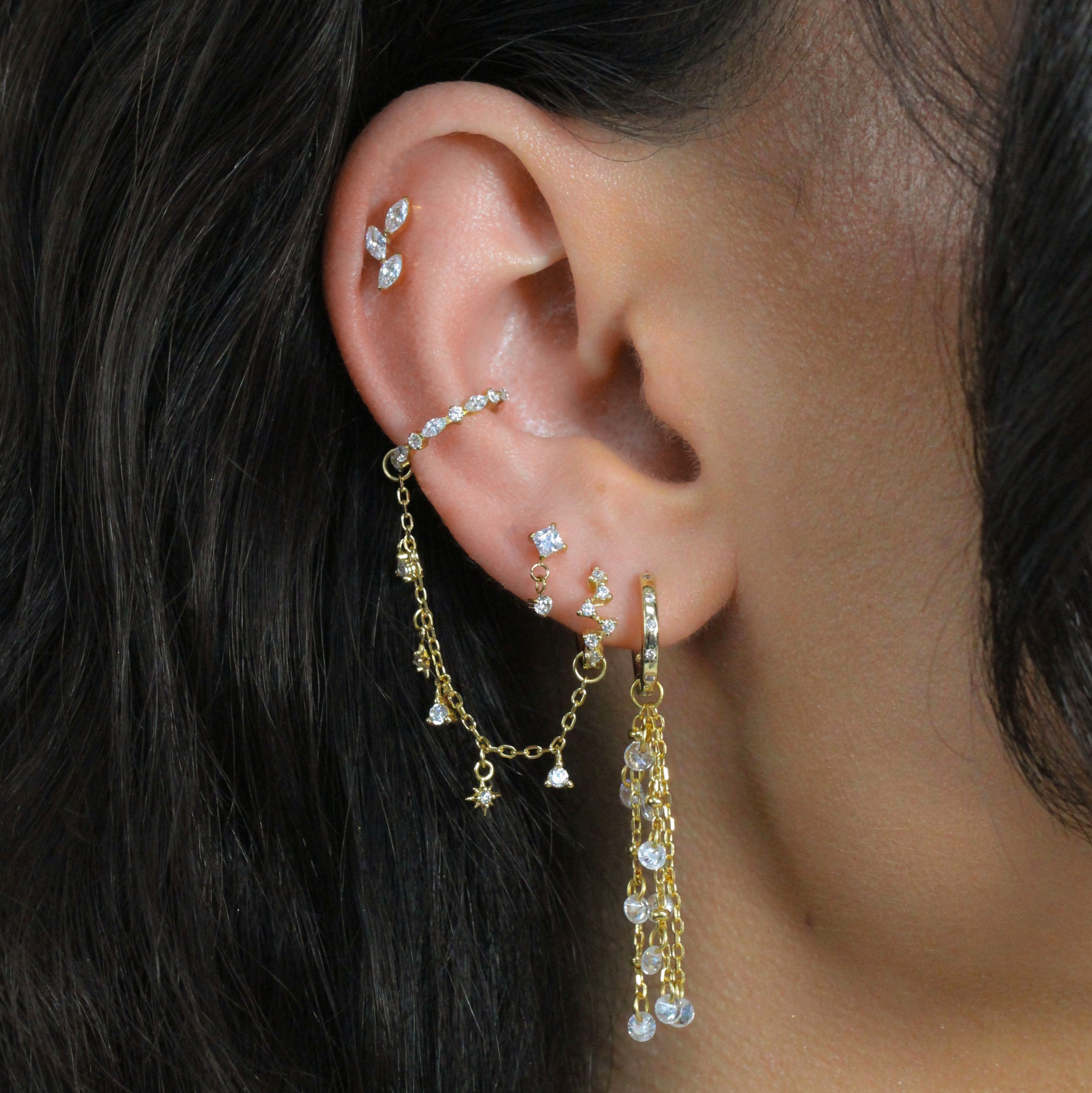 Close-up of an ear stack with SOLEIA Starburst Chain Charm by Crystal Heaven London and sleek cuffs.