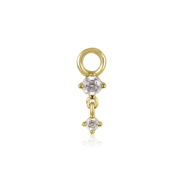 The Crystal Heaven London VOGUE Droplet Charm features a gold pendant with two round clear stones, resembling cubic zirconia. A larger stone is elegantly positioned above a smaller one, and it includes a small circular loop for stylish attachment.